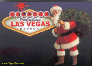 A santa clause is standing in front of the las vegas sign.